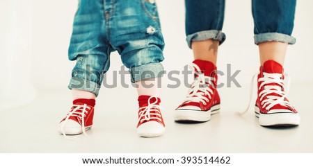 legs mother and child on a white background dressed in blue jeans and red sneakers legs mother and child on a white background dressed in blue jeans and red sneakers in a standing position