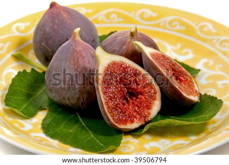 a plate of fresh figs arranged on a fig leaf