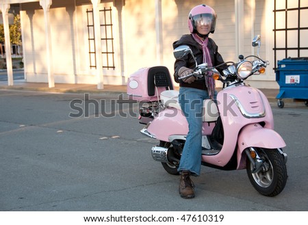 a sixty year old biker stopping on the street in her pink scooter