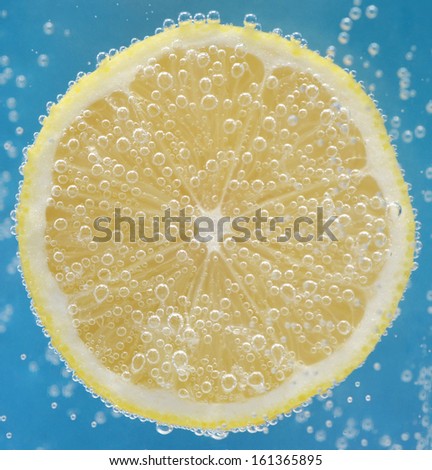 Lemon slice in bubbly water on blue background/Fresh lemon slice/Abstract fruit