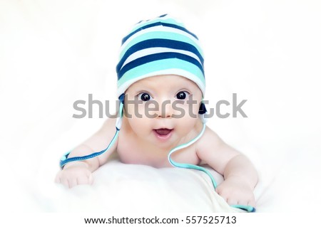 Surprised cute baby in a hat lying on a belly and looking at the viewer