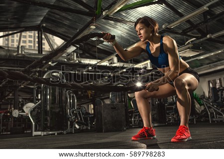 Female athlete working out with heavy ropes at the gym