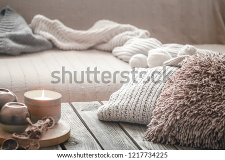still life from home interior on a wooden background with a candle and pillows, home comfort concept