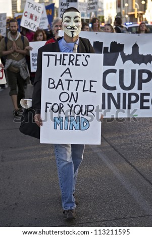 WINNIPEG, CANADA - SEPTEMBER 17: An unidentified protester wearing a Guy Fawkes mask marches with a sign in front of Occupy Winnipeg\'s demonstration marking of Occupy Wall Street\'s first anniversary.