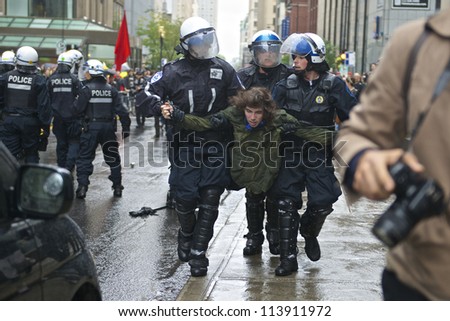 MONTREAL, CANADA - SEPTEMBER 22: Police in riot gear carry an unidentified protester after he damaged a police vehicle from a student rally demanding free tuition on September 22, 2012 in Montreal.
