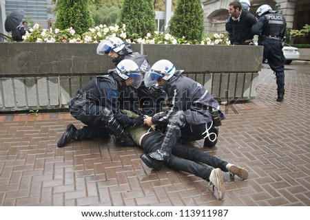 MONTREAL, CANADA - SEPTEMBER 22: Riot police arrest unidentified protesters who damaged a police vehicle while taking part in a march demanding free education on September 22, 2012 in Montreal.