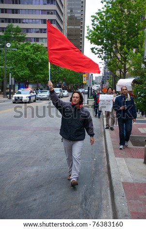 DALLAS - MAY 1: An unidentified demonstrator carries a red flag down Main Street on May 1, 2011 in Dallas, Texas. A red flag flown on May Day is generally considered an endorsement of socialism.