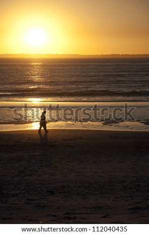 Couple walking hand in hand on a beach at sunset