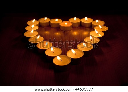 Heart shape made of small flaming candles