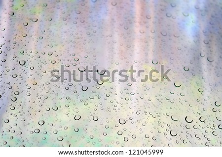 Drops of rain on the window. Unfocused autumn landscape with forest.