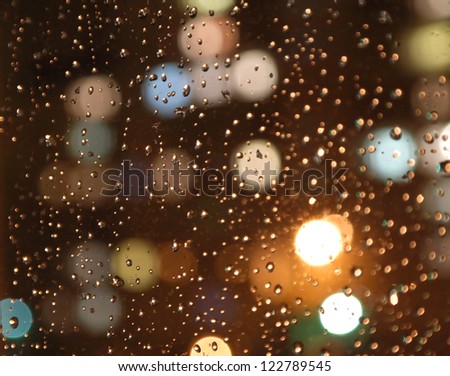 Drops of rain on window, night. On back plan washed away lights of the torches. Shallow DOF