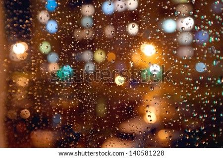 Drops of night rain on window, on back plan washed away lights of the torches. Shallow DOF