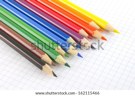 Color pencils on the checked paper of notepad