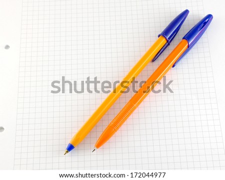 Two pen on the checked paper of notepad