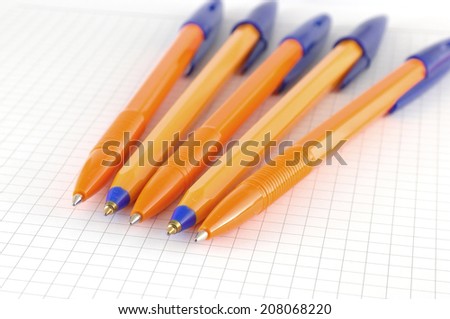Five pen on the checked paper of notepad. Shallow DOF