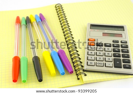 Old calculator and color pens on the yellow writing-book