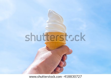 Soft white cream milk ice cream cone serve in hot summer day on sky background