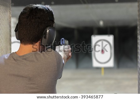 man firing usp pistol at target in indoor fining range