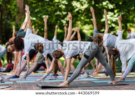 Group free exercise class for people of different age and gender in the city park. International Day of Yoga, summer