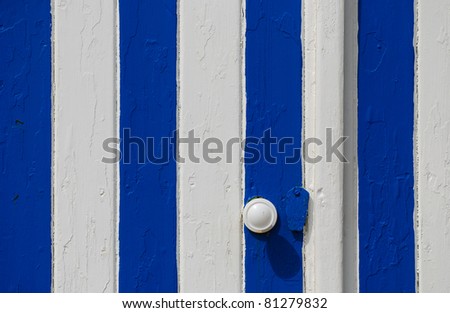 Door of a beach holiday house painted in a typical striped blue and white pattern