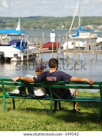 Couple relaxing along the waterfront with docked boats in the background.
