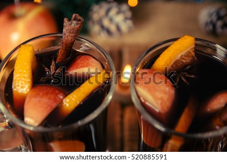 Close up of Christmas mulled wine with fruits, candles  and spices background. Winter warming drink with recipe ingredients. Top view. Two cup.