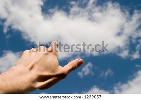 hand pointing the blue sky with white clouds