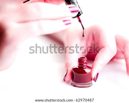 Closeup of woman hands holding bottle of nail polish, nail polish dripping