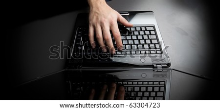 typing on the keyboard of a laptop against a black background