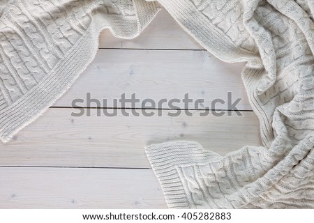 white knitted blanket. lying on white wooden floor in soft folds. in the centre of the empty place of inscription, text.