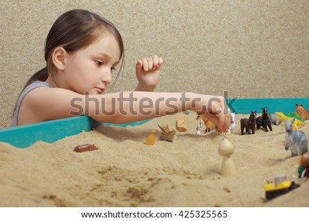 sand therapy. the child playing with the sand. toys in the sand. the psychologist works with the child.