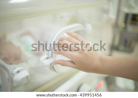 Soft focus Hand of a nurse or doctor checking a baby in the incubator , In neonatal intensive care unit of the hospital. Blurred background.