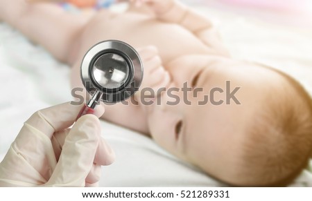 Professional pediatrician examining infant in the hospital. Stethoscope in doctor\'s hand and Blurred background of cute  baby on the towel.