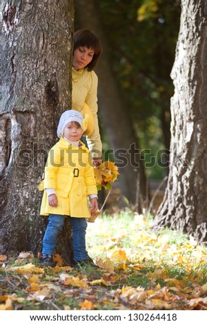 Mother and daughter in autumn forest standing near a tree / Mother and daughter in the autumn forest