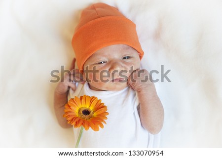 Cute newborn baby in an orange hat with orange flower