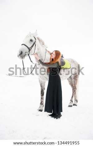 Beautiful girl with long hair embraces a white horse