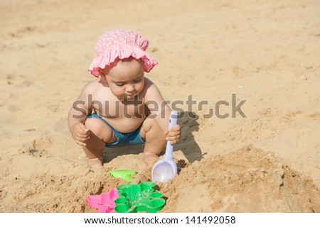 A child plays with sand on the beach