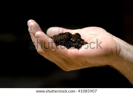 Man\'s hand keeping a piece of ground - black background.