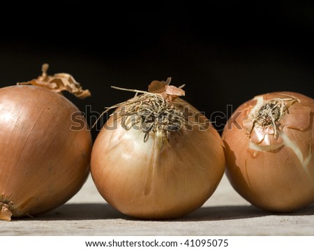 Three onions on a board - black background.