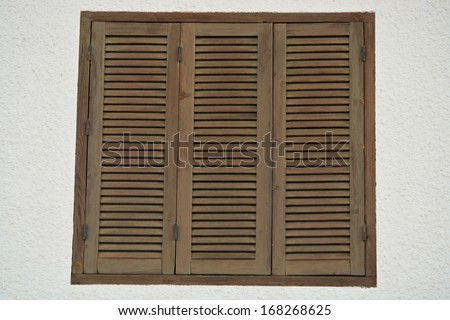 Window with three brown hinged closed shutters