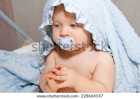 Bliue eyes baby boy with soother, covered blue towel on head