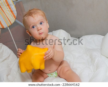 Baby boy with yellow pig moneybox in hands