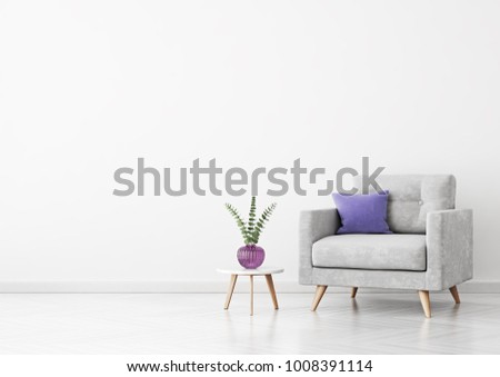 Living room interior with grey velvet armchair, violet pillow, vase and coffee table on empty white wall background. 3D rendering.