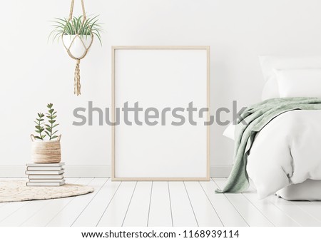 Poster mockup with wooden vertical frame standing on floor in bedroom interior with bed, green plaid and plants on white wall. 3D rendering.