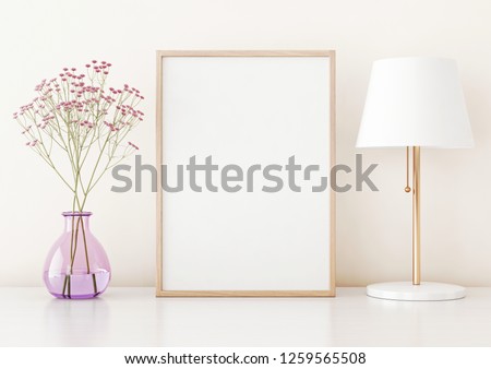 Home interior poster mock up with vertical frame on table, flowers in vase and lamp on warm white wall background. 3D rendering.