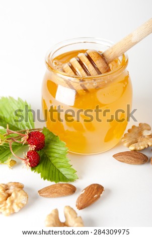 Glass jar of honey with wooden drizzler isolated on white background