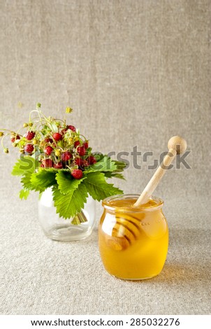 Glass jar of honey with wooden drizzle