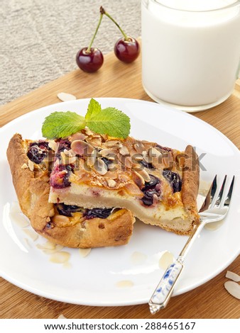 Slices of cherry pie  with almonds and glass of milk