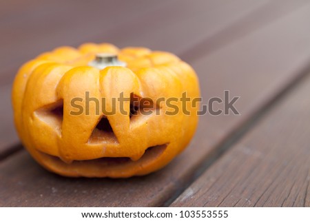 A mini pumpkin carved with a scary face for halloween