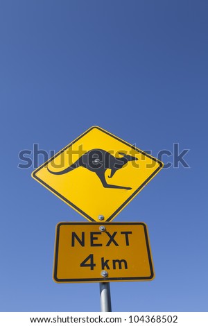 An Australian kangaroo warning road sign against a vibrant blue sky.